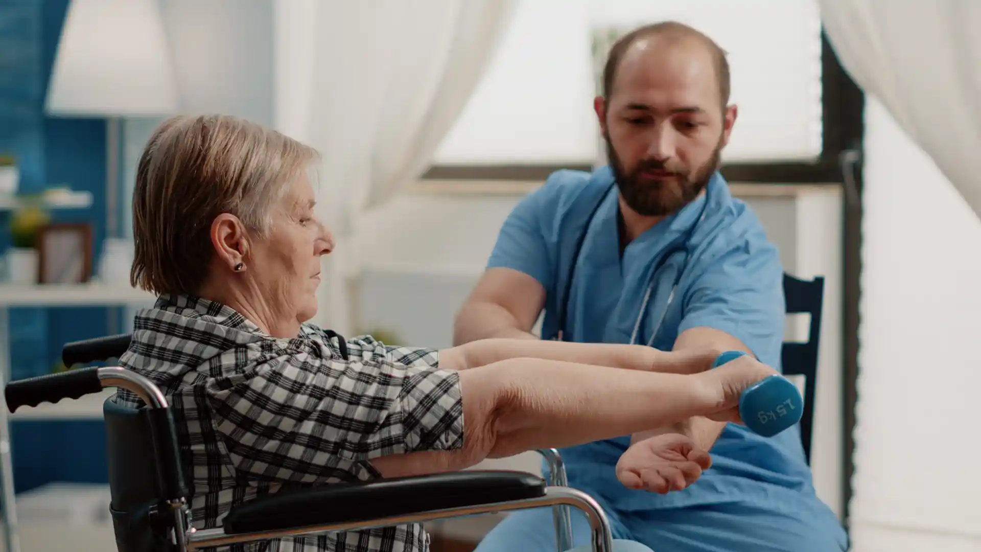 nurse-assisting-disabled-patient-with-physical-exercises-recovery-retired-woman-sitting-wheelchair-using-dumbbells-healing-activity-nursing-home-while-nurse-giving-support Post-Stroke Recovery